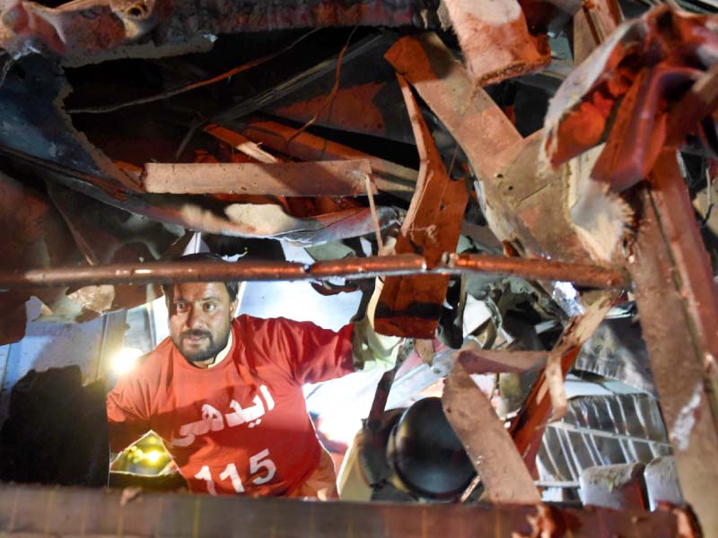 a volunteer searches the damaged bus in quetta photo afp