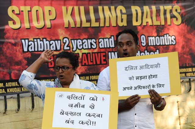 an indian social activist adjusts a banner for a protest over the killing of children in an arson attack in new delhi on october 21 2015 photo afp