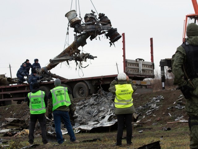 members of the dutch export team watch as parts of the wreckage of the malaysia airlines flight mh17 are removed and loaded on a truck at the crash site near the village of grabove in eastern ukraine on november 16 2014 photo afp