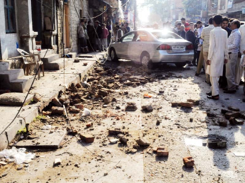 people gather around a car which was hit by a wall that fell during the earthquake on alam khan road in rawalpindi people stand outside buildings in blue area islamabad after the jolts photos agha mehroz mudassar raja express