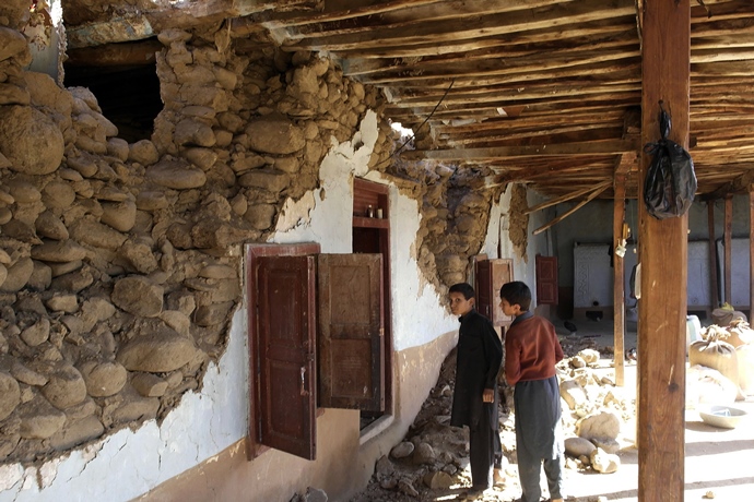 young children look at a damaged house following an earthquake in lower dir on october 27 2015 photo afp