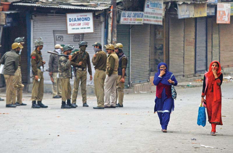 women walk past a police patrol in srinagar photo afp