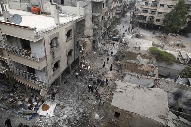 a picture taken on october 29 2015 shows syrians inspecting damaged buildings following a reported air strike by syrian government forces in the rebel held area of douma east of the capital damascus photo afp