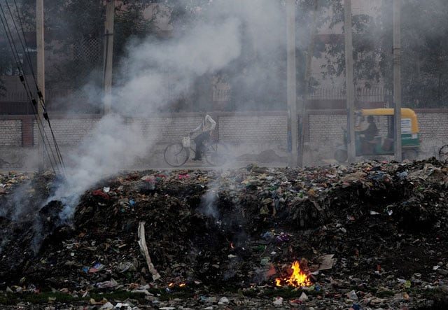 in this photograph taken on february 18 2015 indian people pass by garbage that is dumped and burnt on the roadside in faridabad on the outskirts of new delhi photo afp in this photograph taken on february 18 2015 indian people pass by garbage that is dumped and burnt on the roadside in faridabad on the outskirts of new delhi photo afp