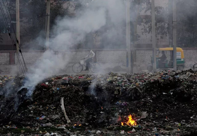 in this photograph taken on february 18 2015 indian people pass by garbage that is dumped and burnt on the roadside in faridabad on the outskirts of new delhi photo afp in this photograph taken on february 18 2015 indian people pass by garbage that is dumped and burnt on the roadside in faridabad on the outskirts of new delhi photo afp