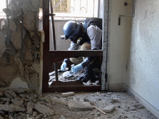 a united nations weapons expert collects samples during an investigation into a 2013 suspected chemical weapons strike near damascus photo afp