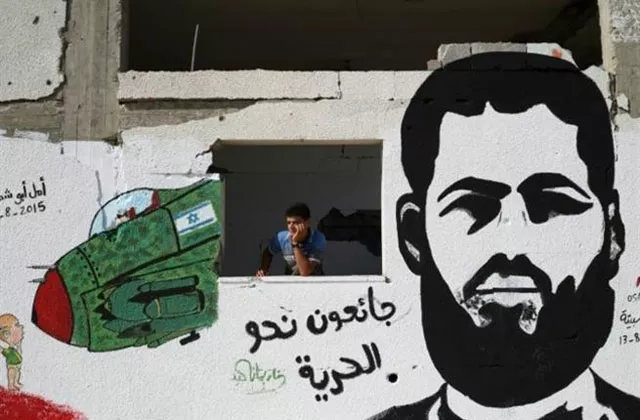 a palestinian youth stands behind a wall sprayed with a graffiti depicting 31 year old muhammed allan photo afp a palestinian youth stands behind a wall sprayed with a graffiti depicting 31 year old muhammed allan photo afp
