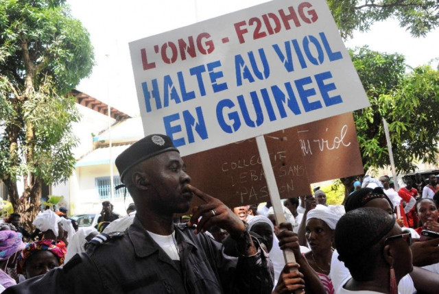 a police officer stands next to a woman holding a sign reading quot stop rape in guinea quot during a protest march against women photo afp a police officer stands next to a woman holding a sign reading quot stop rape in guinea quot during a protest march against women photo afp