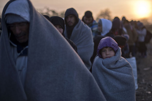 a young migrant is covered with a blanket as migrants and and refugees wait to enter a registration camp near gevgelija on october 30 2015 photo afp