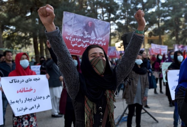 afghan solidarity members hold posters and chant slogans as they stage a protest against taliban militants who stoned an afghan woman to death at shar e naw park in kabul on november 6 2015 photo afp