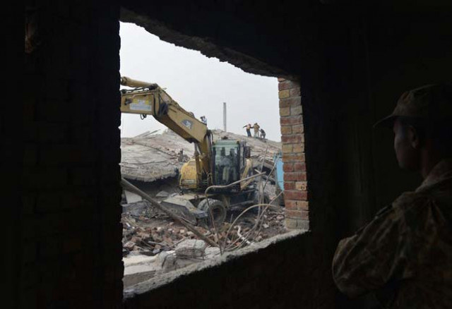 a rescuer uses a excavator to remove rubble of a collapsed factory on the outskirts of lahore on november 5 2015 photo afp a rescuer uses a excavator to remove rubble of a collapsed factory on the outskirts of lahore on november 5 2015 photo afp
