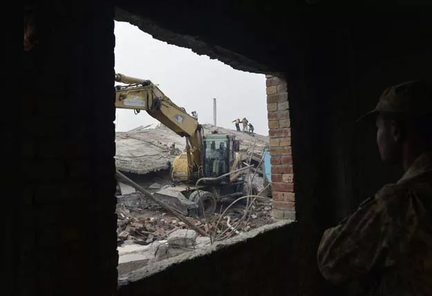a rescuer uses a excavator to remove rubble of a collapsed factory on the outskirts of lahore on november 5 2015 photo afp a rescuer uses a excavator to remove rubble of a collapsed factory on the outskirts of lahore on november 5 2015 photo afp