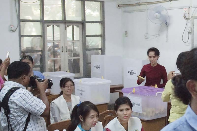 onlookers peer through a window as aung san suu kyi casts her vote at a polling station in yangon photo afp