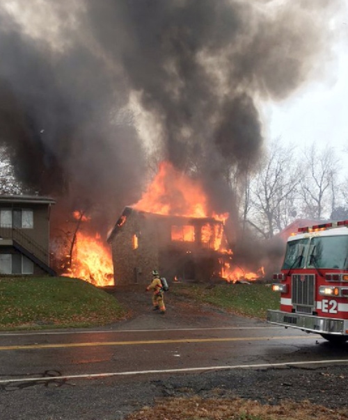 a firefighter walks up a driveway as an apartment building burns in akron tuesday where authorities say a small business jet crashed the plane burst into flames and disintegrated after impact photo akron beach journal