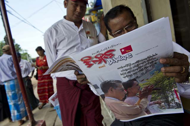 myanmar men read a newspaper showing a picture of opposition leader aung san suu kyi seen at right with tin oo the national league for democracy nld party chairman outside the nld headquarters in yangon on november 11 2015 photo afp