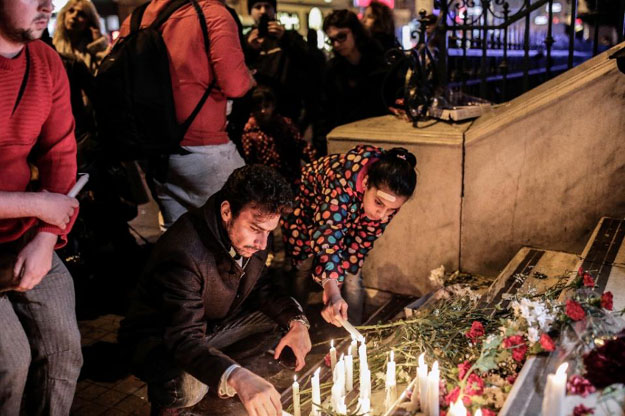 people hold candles and lay floral tributes at the french consulate in istanbul on november 14 2015 photo afp