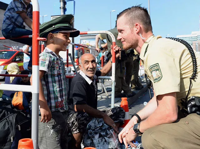 a german police officer lets a refugee child wear his cap while waiting for a bus at the main train station in munich southern germany photo afp a german police officer lets a refugee child wear his cap while waiting for a bus at the main train station in munich southern germany photo afp
