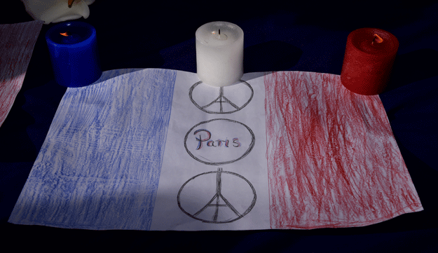 red white and blue candles are displayed with a drawing of the french flag during a remembrance service in civic square wellington on november 17 2015 photo afp