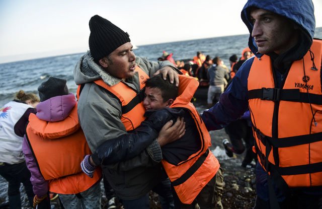 people react after arriving on the greek island of lesbos along with other migrants and refugees on november 17 2015 after crossing the aegean sea from turkey photo afp