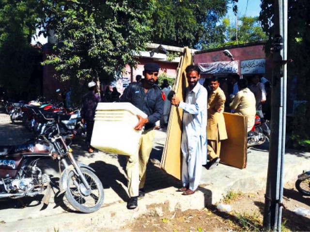 a policeman helps ecp staff move election material to a polling station in chiniot photo online a policeman helps ecp staff move election material to a polling station in chiniot photo online