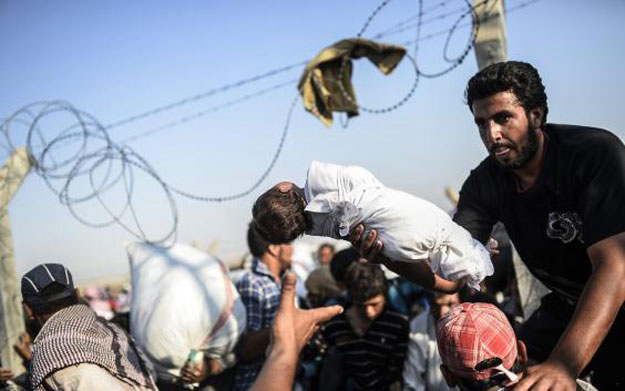 a syrian man passes his newborn child over the akcakale border in order to cross into turkish territories photo afp