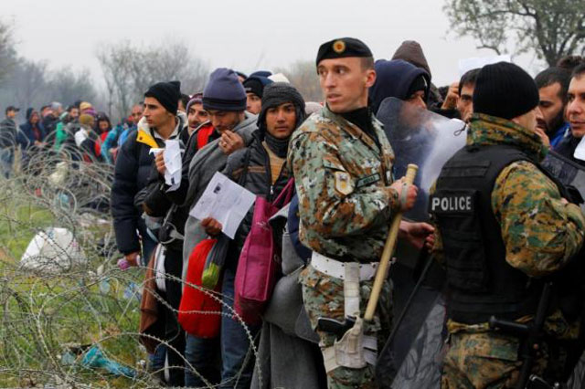 migrants hold their documets as they are blocked by macedonian policemen at the border with greece photo reuters