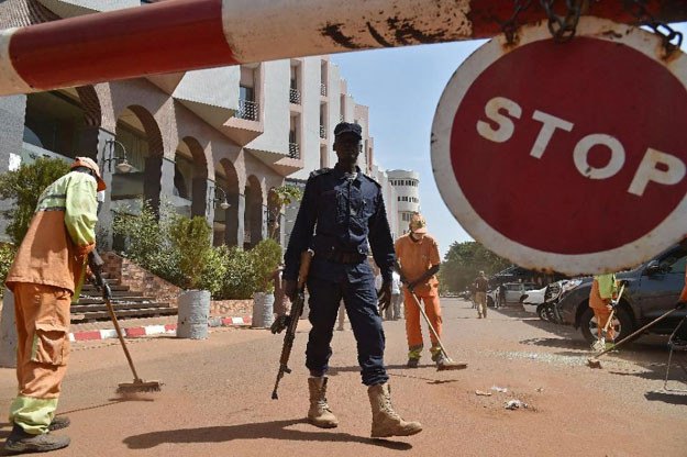 a malian police officer stands guard as municipal workers clean outside the radisson blu hotel in bamako on november 22 2015 two days after a deadly attack photo afp