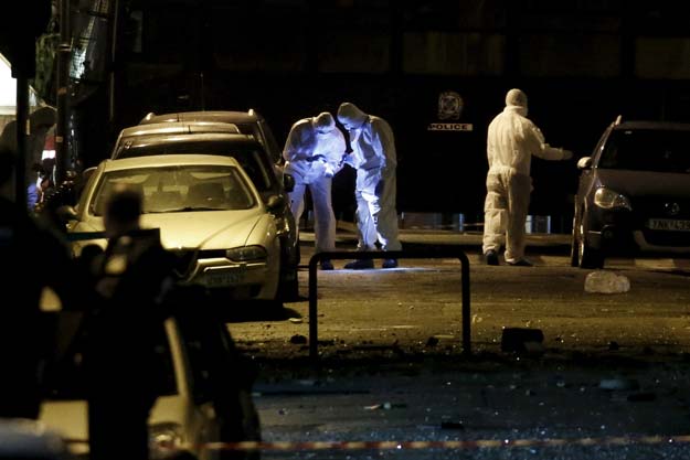 forensic experts search for evidence on a street where a bomb exploded outside the entrance of the hellenic business federation offices in athens greece november 24 2015 a bomb exploded outside the offices of a greek business federation in central athens early on tuesday police officials said smashing windows but causing no injuries photo reuters