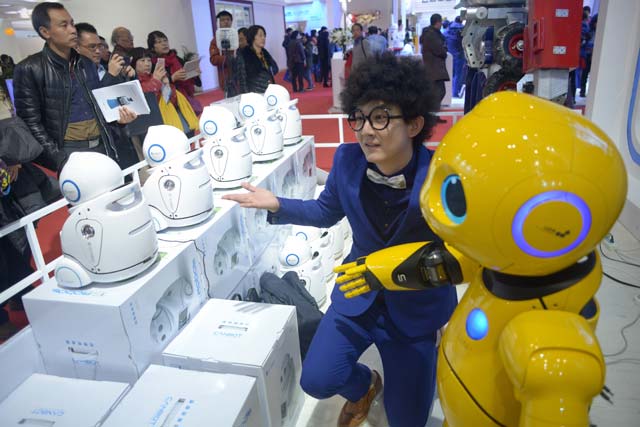 this picture taken on november 24 2015 shows a visitor posing for a photo with a robot during the world robot conference in beijing beijing wants to be the first to welcome the new mechanical overlords and the world robot conference showcases a vision of automatons with chinese characteristics photo afp
