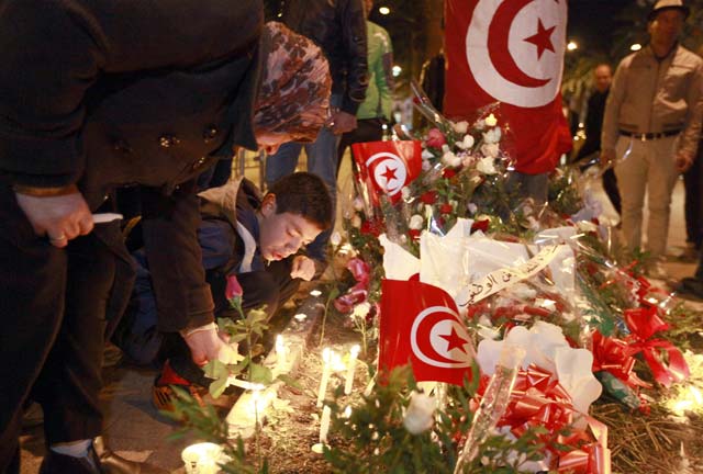 tunisians light candles during a vigil on november 25 2015 at the site of the attack on a bus in central tunis which killed several presidential guards the previous day the islamic state group claimed the deadly bombing of a presidential guard bus in the tunisian capital in a statement shared on jihadist social media accounts photo afp