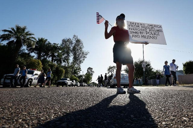 a protester holds an american flag and a sign as he stands outside the islamic community center on may 29 2015 in phoenix arizona photo afp a protester holds an american flag and a sign as he stands outside the islamic community center on may 29 2015 in phoenix arizona photo afp