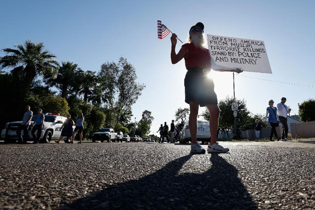 a protester holds an american flag and a sign as he stands outside the islamic community center on may 29 2015 in phoenix arizona photo afp