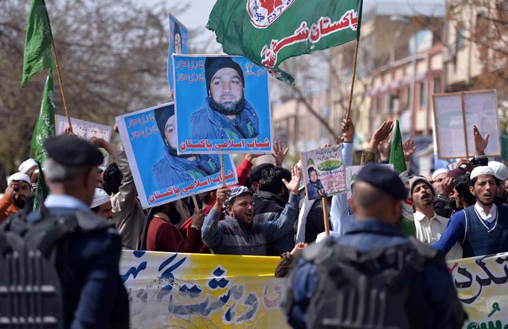 supporters of former police bodyguard mumtaz qadri hold posters bearing his image as they gather opposite a police cordon outside the high court in islamabad photo afp