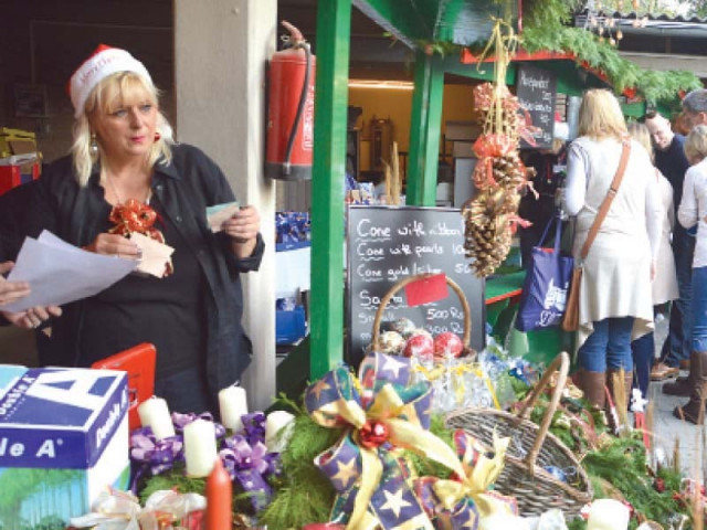 a woman running a stall selling candles and other christmas decorations photo mudassar raja a woman running a stall selling candles and other christmas decorations photo mudassar raja