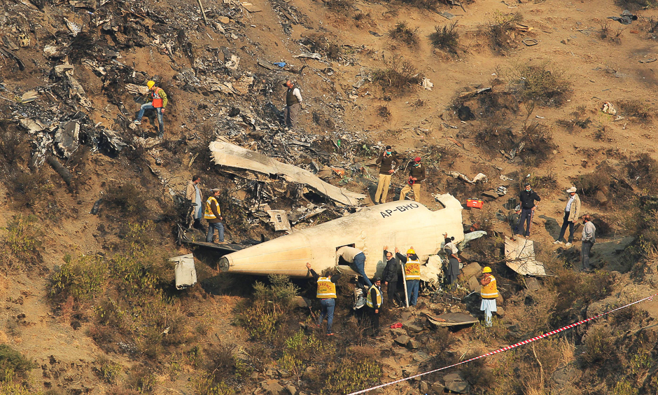 Rescue workers survey the site of a plane crashed a day earlier near the village of Saddha Batolni, near Abbotabad, Pakistan, December 8, 2016. REUTERS/Faisal Mahmood