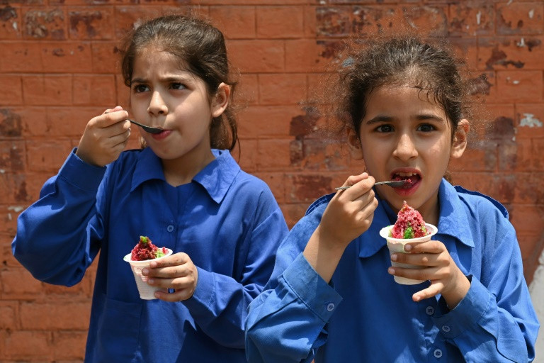 students eat ice cream outside their school in lahore where schools will close a week early because of extreme temperatures photo afp