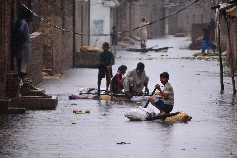 residents use makeshift rafts to make their way along a waterlogged street in a residential area of hyderabad sindh photo afp