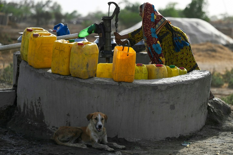 a woman fills containers with water from a hand pump during a heatwave in jacobabad photo afp