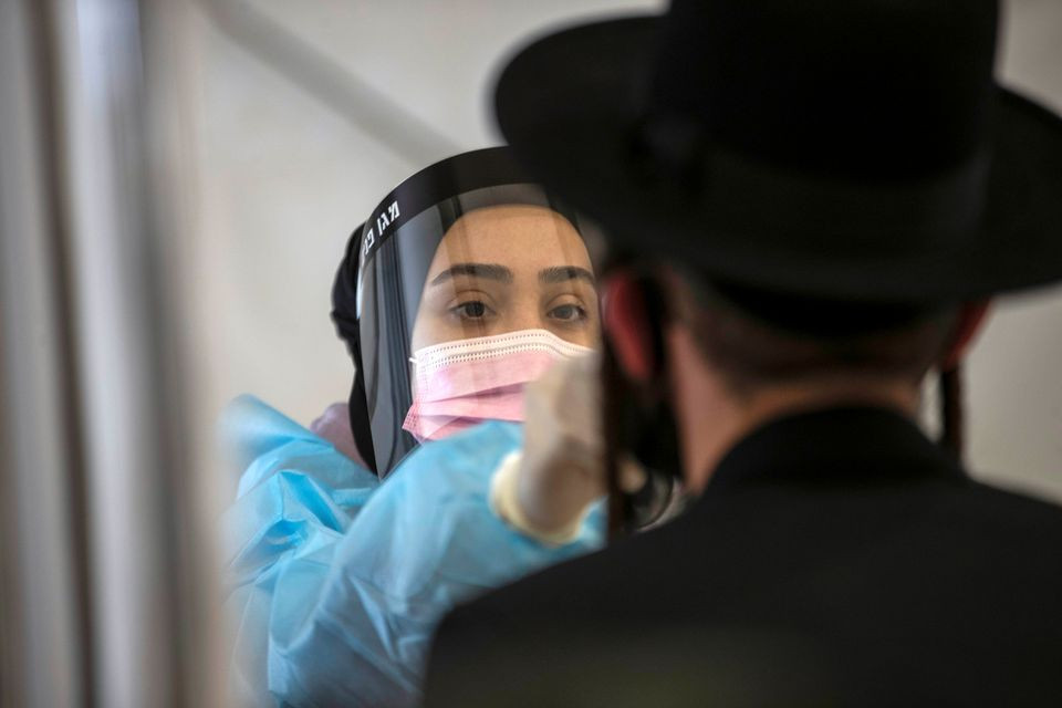 a healthcare worker takes a swab sample from an ultra orthodox jewish man for the coronavirus disease covid 19 test after returning from overseas at ben gurion international airport in lod near tel aviv israel april 13 2021 reuters