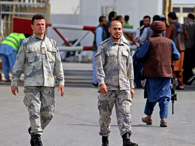 afghan policemen walk past a taliban fighter r outside the airport in kabul on sunday photo afp afghan policemen walk past a taliban fighter r outside the airport in kabul on sunday photo afp