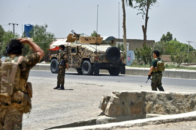 Afghan security personnel stand guard along a road in Kandahar during fighting between Afghan security forces and Taliban fighters. PHOTO: AFP