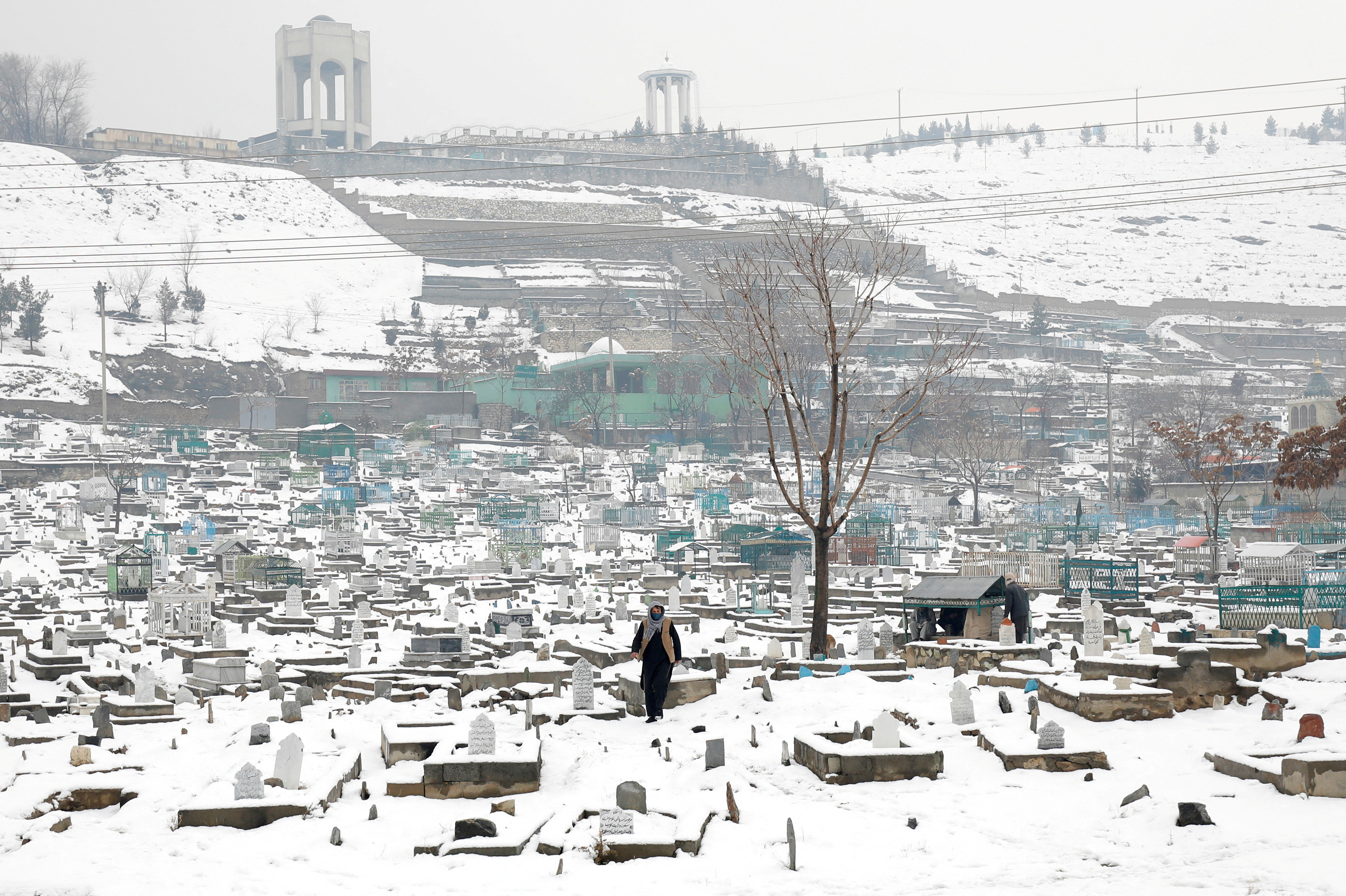 an afghan man walks on a snow covered cemetery in kabul afghanistan january 11 2023 reuters ali khara file photo