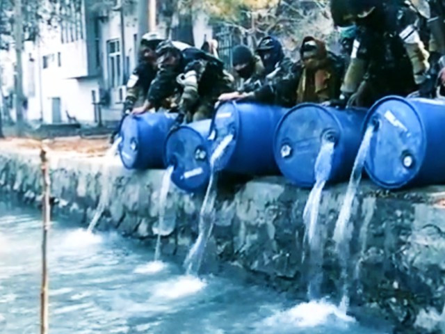 screengrab from video footage released by the general directorate of intelligence gdi showing its agents pouring alcohol stored in barrels into a canal in kabul
