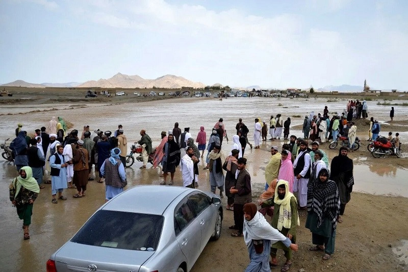 afghan people wait to cross a flooded area in spin boldak district of kandahar province on april 13 2024 photo afp