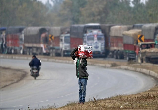 a man carries a box of apples next to parked supply trucks loaded with apples on a highway near qazigund in south kashmir s anantnag district october 17 2019 photo reuters