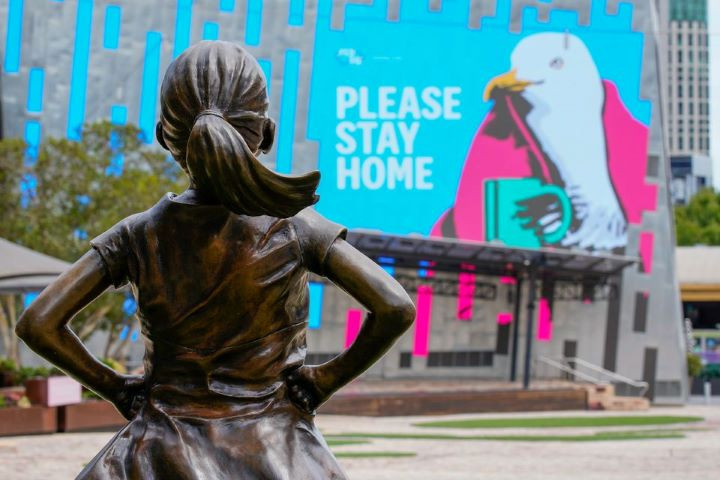 the fearless girl statue looks at a please stay home sign in an empty federation square on the first day of a five day lockdown implemented in the state of victoria in response to the coronavirus disease covid 19 outbreak in melbourne australia february 13 2021 reuters sandra sanders