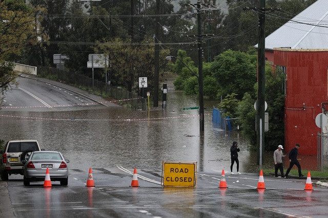 people walk on a street inundated with floodwaters in the suburb of windsor as the state of new south wales experiences widespread flooding and severe weather in sydney australia march 22 2021 photo reuters