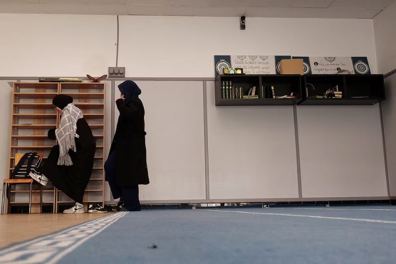 Students wearing abayas put their shoes back on as they prepare to leave the prayer room at the Averroes school, in Lille, France, March 19, 2024. PHOTO: REUTERS/