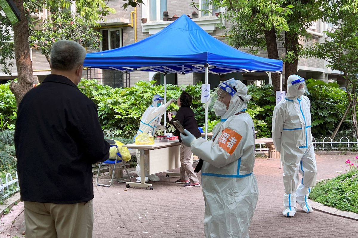 a medical worker in a protective suit collects swab from a resident at a makeshift nucleic acid testing site inside a residential compound under lockdown amid the coronavirus disease covid 19 outbreak in shanghai china april 19 2022 reuters xihao jiang file photo