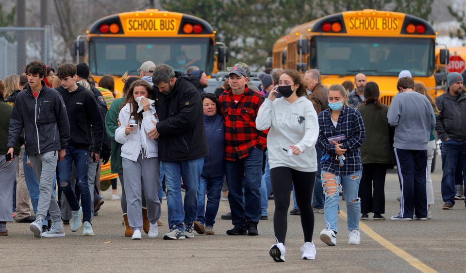 parents walk away with their kids from the meijer s parking lot where many students gathered following an active shooter situation at oxford high school in oxford michigan us november 30 2021